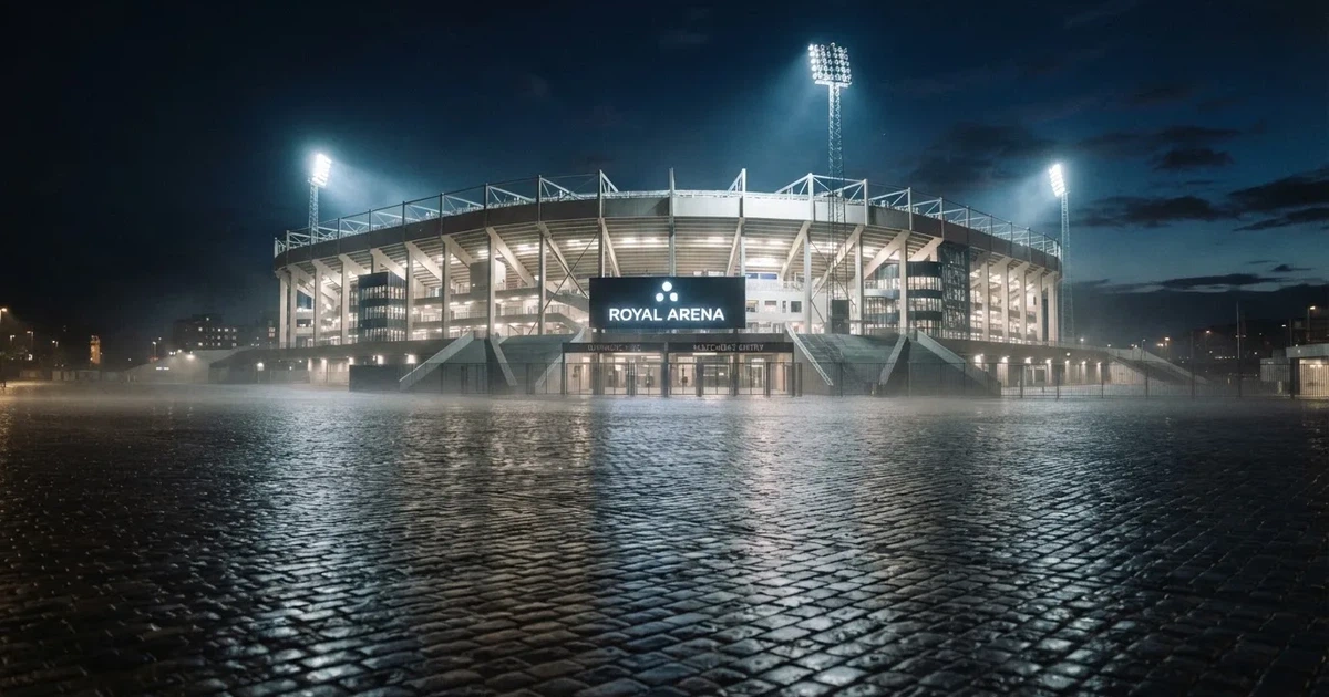 Ein großes Fußballstadion bei Flutlicht von außen, davor ein leerer Vorplatz mit nassem Pflaster und Dunst.