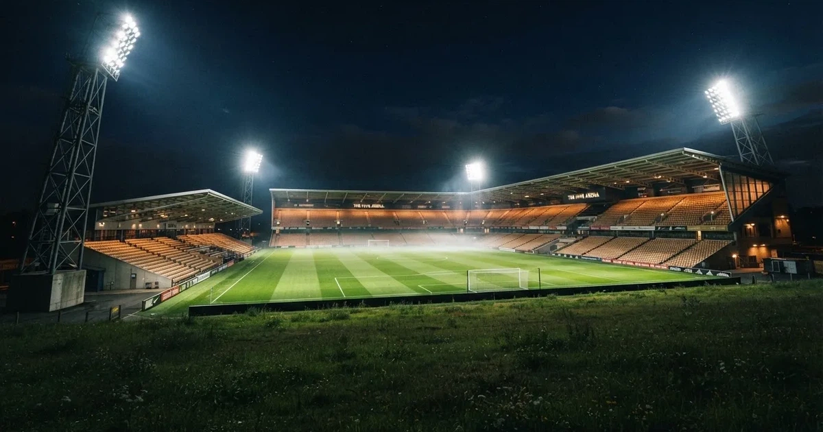 Ein Stadion bei Nacht unter Flutlicht aus der Ferne gesehen, der Rasen ist hell erleuchtet, keine erkennbaren Personen.