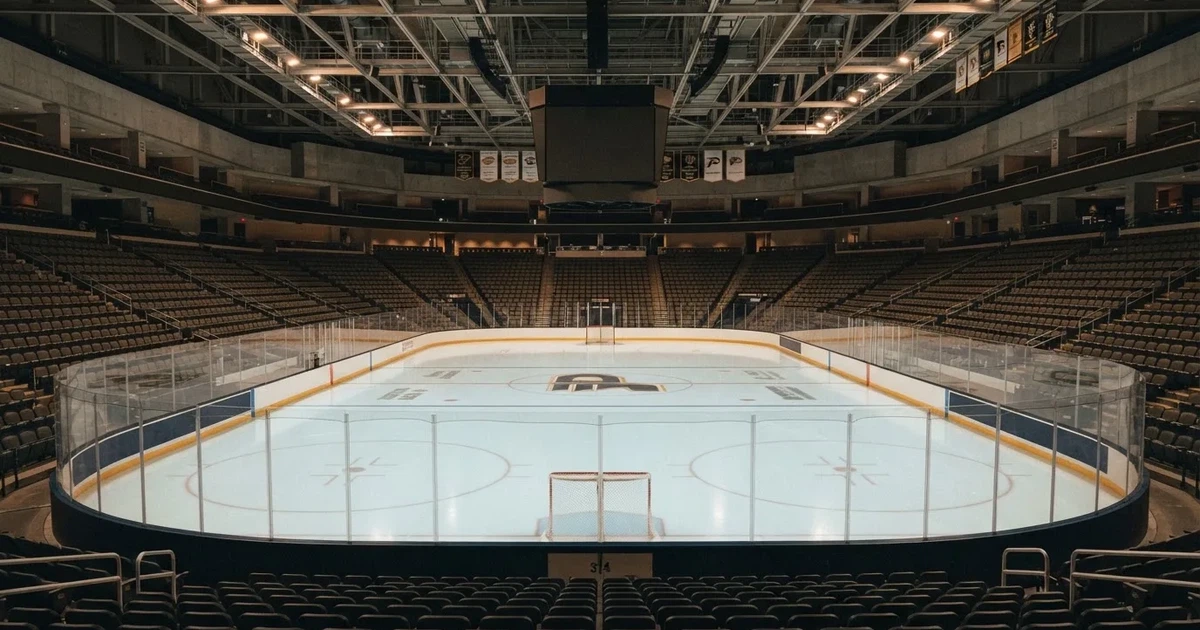 Eine Eishockeyhalle von der Tribüne aus gesehen, spiegelglatte Eisfläche, Banden ohne Schriftzüge, helles Flutlicht.
